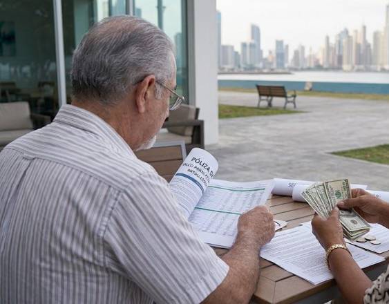 IMAGEN CON IA | Dos adultos mayores revisan documento de pólizas.