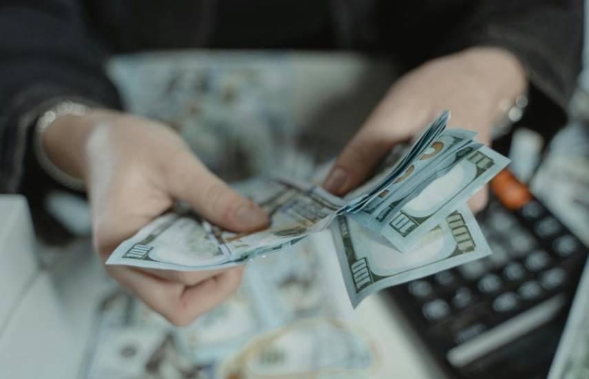 ML | Una persona con billetes de 100 dólares en sus manos.