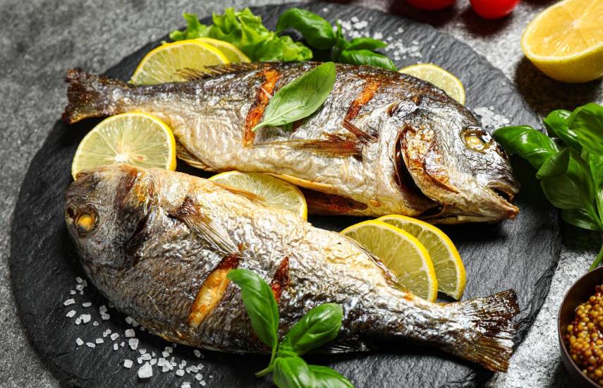 Freepik | Dos pescados asados colocados en un plato con limón.