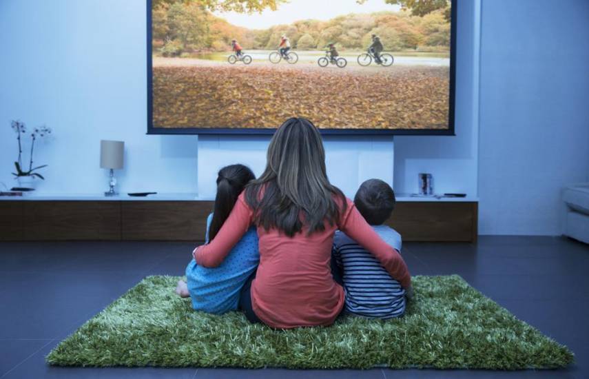 Cortesía | Una madre junto a sus hijos viendo televisión.