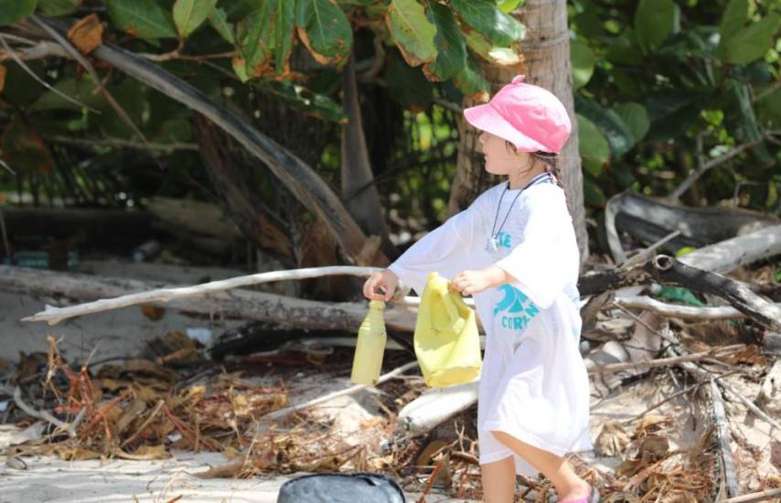 Una niña recoge desechos plásticos en una playa.