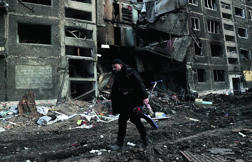 AFP | Un hombre con una scooter de niño pasa junto a un edificio de apartamentos destruido por un ataque con misiles rusos en la ciudad de Selydove, región de Donetsk.