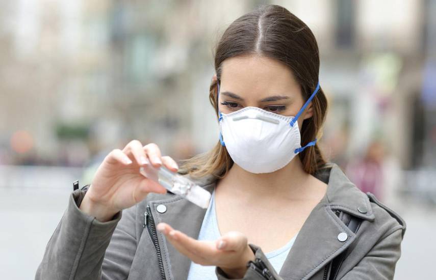 Pixabay | Una mujer con mascarilla, colocándose gel antibacterial.