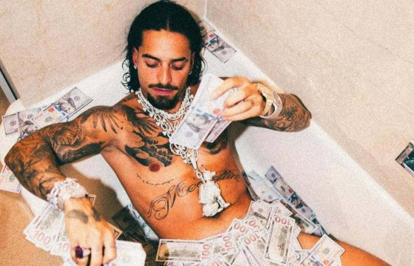 ML | El cantante Maluma en una bañera con muchos billetes de cien dólares.