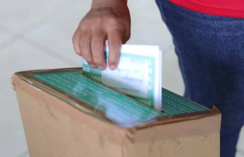 ML | Una persona introduciendo una papeleta de votación en una urna.