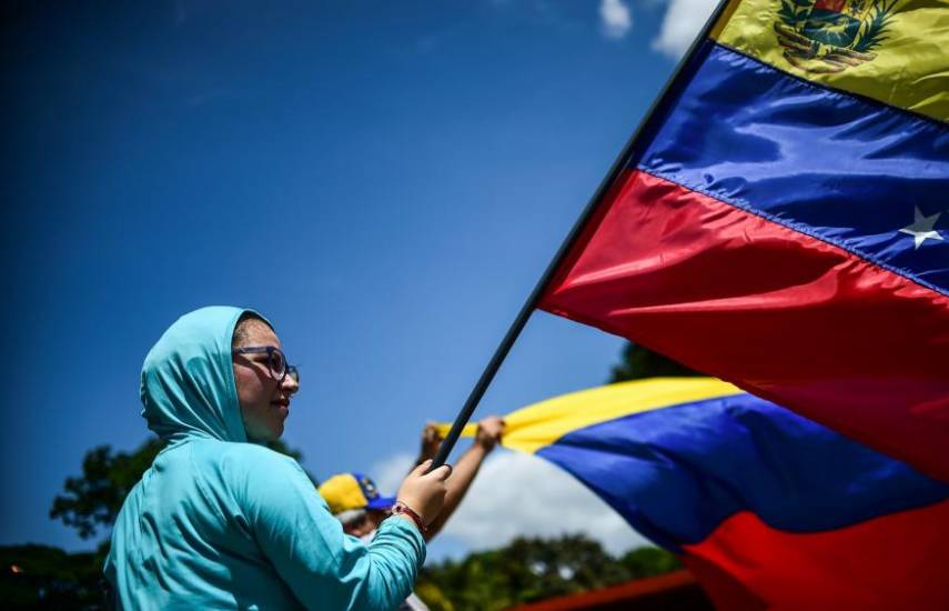 AFP | Una mujer venezolana ondea una bandera de su país de origen en medio de una manifestación.