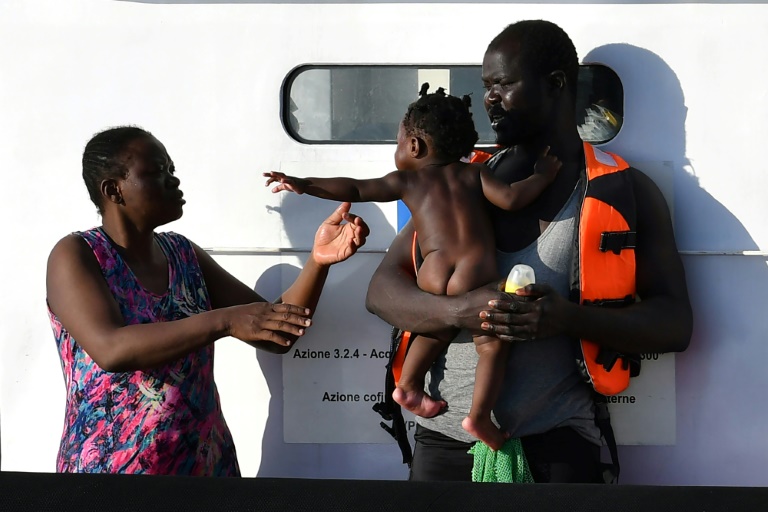 Una pareja de migrantes y su bebé procedentes de Libia esperan a desembarcar de un guardacostas italiano el 31 de julio de 2020 en la isla italiana de Lampedusa