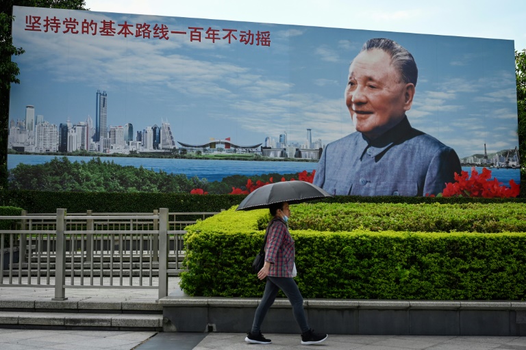 Una mujer pasa por delante de un cartel del líder chino Deng Xiaoping el 13 de julio de 2022 en la ciudad china de Shenzhen