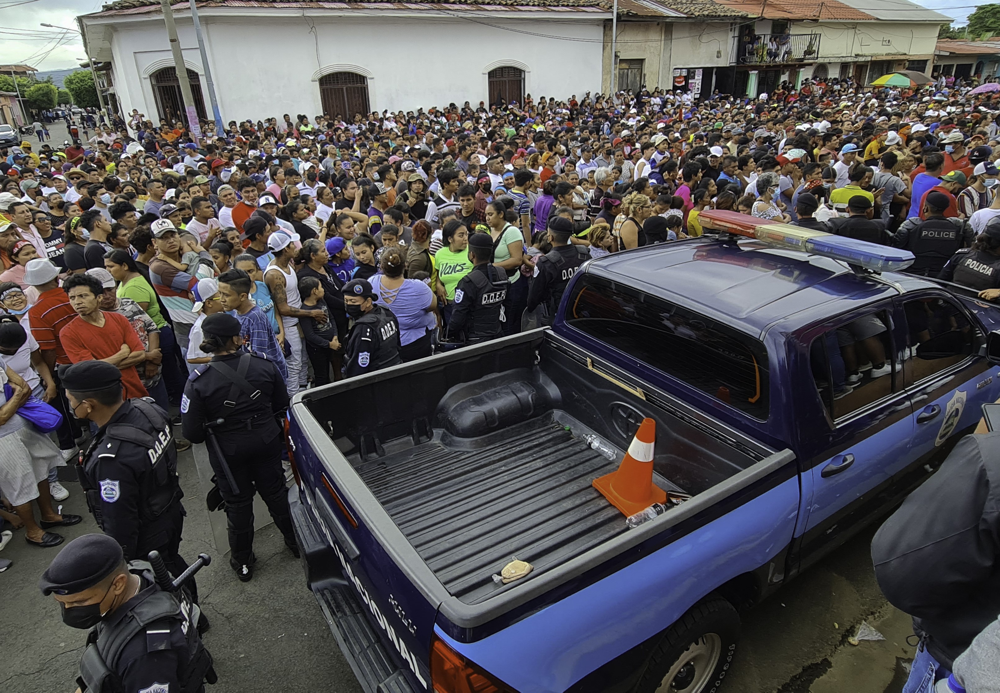 AFP | Unidades de la policía de Nicaragua en medio de una multitud de religiosos, los cuales participan de una procesión