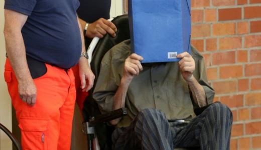 El antiguo guardia en un campo de concentración nazi Josef Schutz se cubre el rostro al llegar al tribunal de Brandenburgo an der Havel, en el este de Alemania, el 28 de junio de 2022 para conocer su veredicto