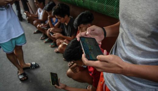 AFP | Jóvenes usan sus teléfonos móviles para jugar Axie Infinity, un juego de NFT en el que los jugadores ganan tokens que pueden canjearse por criptomonedas o efectivo.